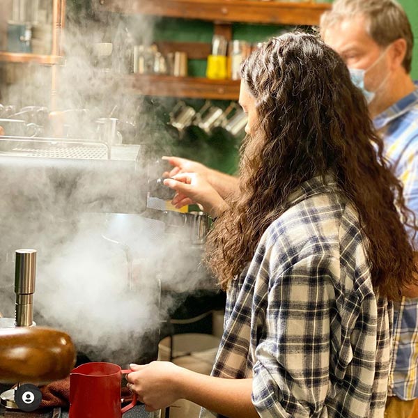 An image of two people making coffee in a cafe.