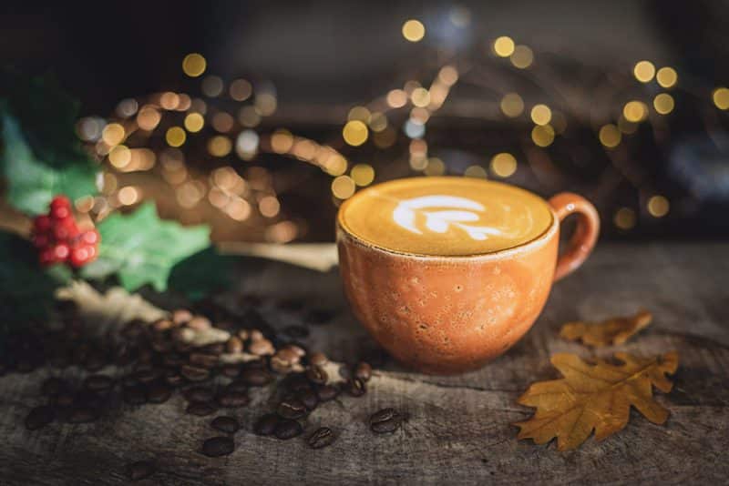 cup of coffee with Christmas holly and lights